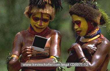 PAPUA NEW GUINEA: Two colorfully dressed members of Huli Tribe having a first look at a polaroid picture (MR) .