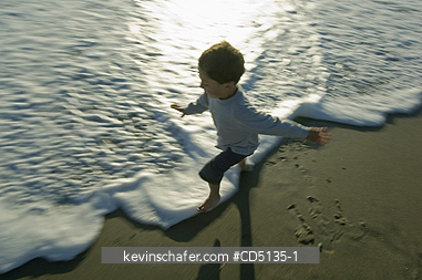 PEOPLE, CHILDREN: Young boy playing in surf on beach,  Oregon coast