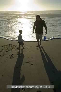 PEOPLE: Young boy playing in surf on beach with adult, 4 years old, Oregon coast, model released.