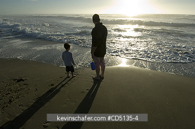 PEOPLE: Young boy playing in surf on beach with adult, 4 years old, Oregon coast, model released.