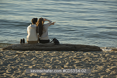 SEATTLE: Couple on beach log, Alki Beach, Seattle, Washington SUMMER