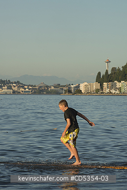 SEATTLE: Summer on Alki Beach, Boy playing on log, West Seattle, Puget Sound, Seattle, Washington  