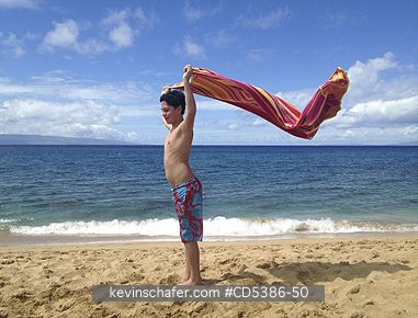 PEOPLE, HAWAII: Boy, aged 12, playing with beach towel, Maui, Hawaii (MOBILE PHONE)