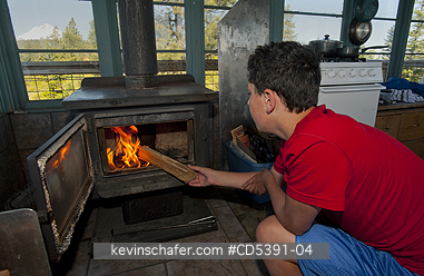OREGON, PEOPLE: Theo Braibish, aged 12, Stoking fire in Five Mile Butte Lookout tower, Mt. Hood National Forest, Oregon