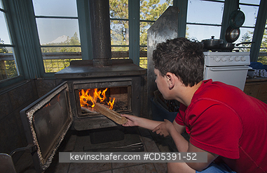 OREGON, PEOPLE: Theo Braibish, age 12, stoking fire in FiveMile Butte Lookout tower, Mt. Hood National Forest, Oregon
