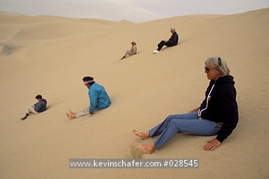 NAMIBIA: Namibia, Skeleton Coast, Group of tourists sliding down the roaring dunes.