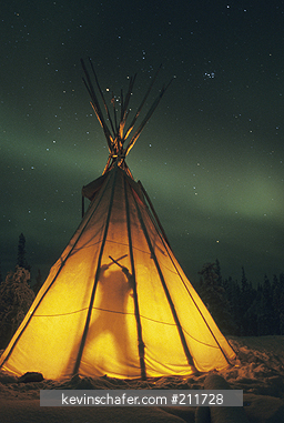 CANADA: Blachford Lake, Great Slave Lake area, near Yellowknife, man in teepee at night with Aurora Borealis, northern lights, Northwest Territories.