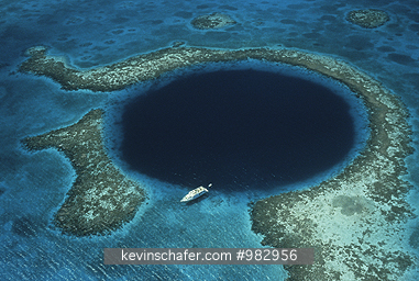 BELIZE: Aerial of The Blue Hole, Collapsed limestone cavern, Lighthouse Reef, Offshore Atoll, Belize Barrier Reef.  Dive boat at anchor.